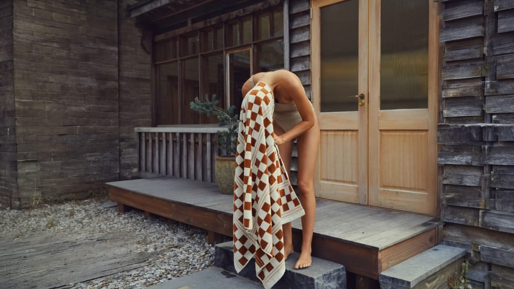 Guest wrapped in a towel on a timber deck after the sauna