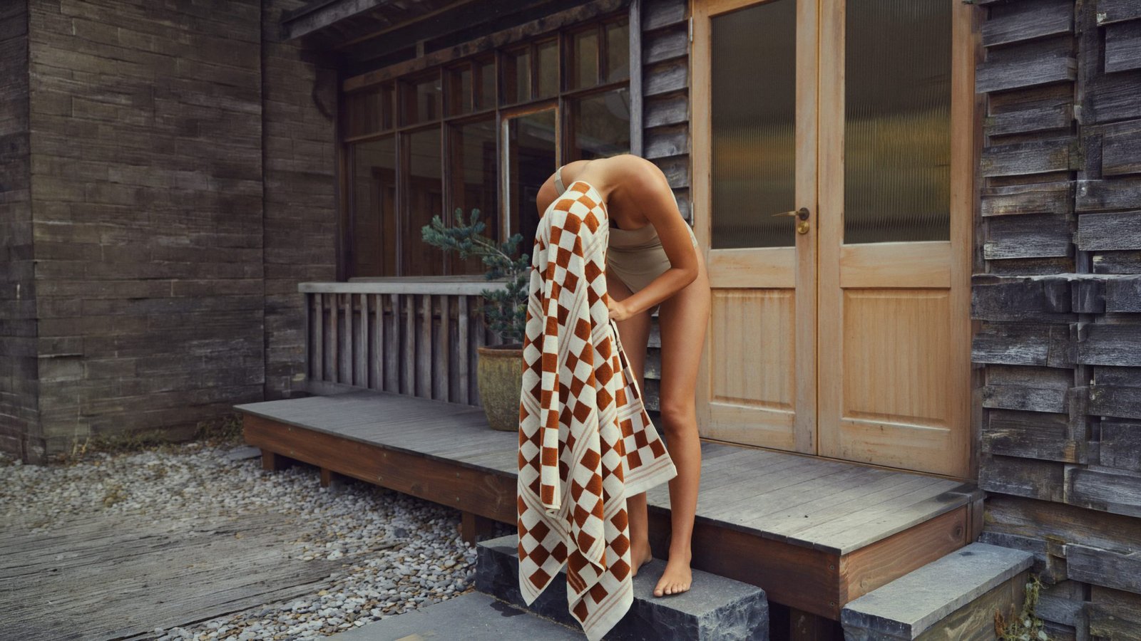 Guest wrapped in a towel on a timber deck after the sauna